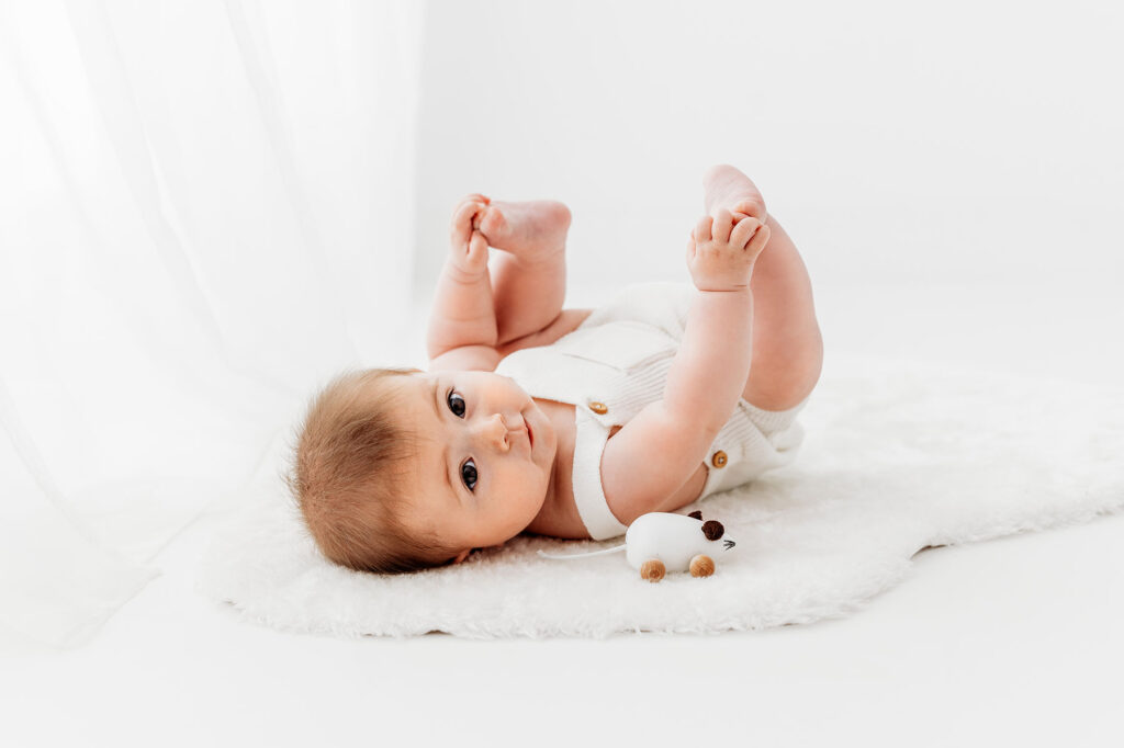 Baby laying on floor touching feet